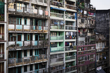 Facade of rows of run down apartment houses with washing hanging on balconies. - MINF13487