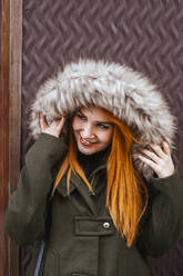 Porträt einer lächelnden rothaarigen jungen Frau mit Kapuzenjacke - LJF01291