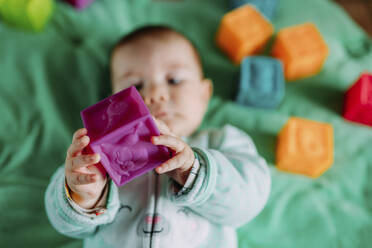 Babyhände halten lila Gummiwürfel, Nahaufnahme - GEMF03422