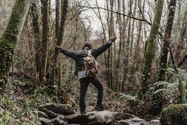 young man with backpack, crossing steam in forest - AFVF05268