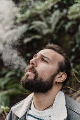 Portrait of young man, smoking outdoors - AFVF05277