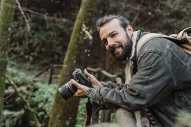 Young man taking pictures in the forest with his camera - AFVF05285