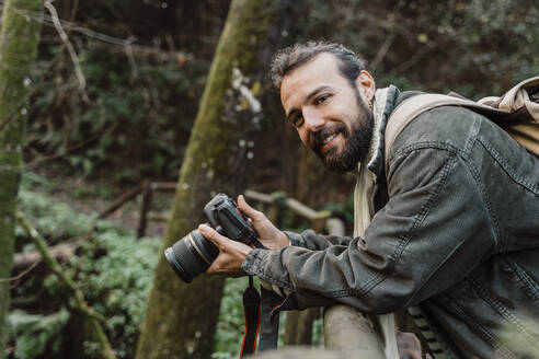 Junger Mann fotografiert im Wald mit seiner Kamera - AFVF05285