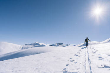 Mann im Gegenlicht auf Skitour, Graubünden, Schweiz - HBIF00021