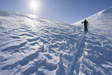 Mann im Gegenlicht auf Skitour, Graubünden, Schweiz - HBIF00025