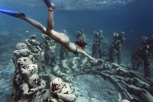 Frau schwimmt in der Nähe einer Unterwasserskulptur von Jason deCaires Taylor, Insel Gili Meno, Bali, Indonesien - KNTF04331