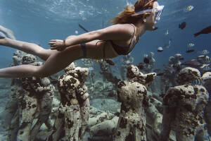 Frau schwimmt in der Nähe einer Unterwasserskulptur von Jason deCaires Taylor, Insel Gili Meno, Bali, Indonesien - KNTF04336