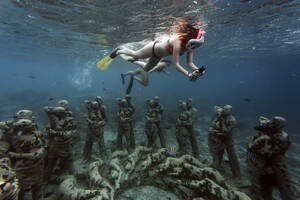 Frauen schwimmen in der Nähe von Unterwasserskulpturen von Jason deCaires Taylor, Insel Gili Meno, Bali, Indonesien - KNTF04342