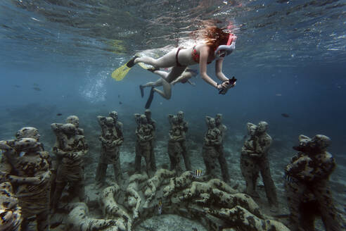 Frauen schwimmen in der Nähe von Unterwasserskulpturen von Jason deCaires Taylor, Insel Gili Meno, Bali, Indonesien - KNTF04342