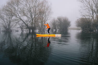 Frau Stand Up Paddle Surfing auf einem See - DGOF00304