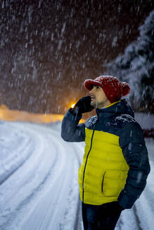 Man on the phone in snowfall at night - CJMF00243