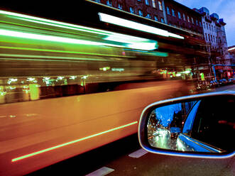 Deutschland, Berlin, Seitenspiegel eines Autos, das in der Abenddämmerung durch die Stadt fährt - BIGF00069
