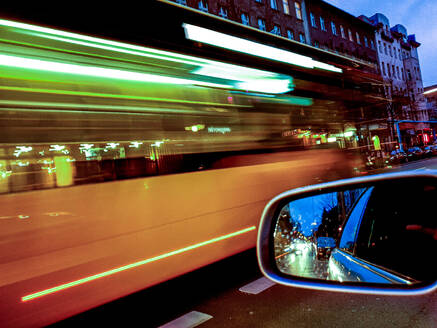 Germany, Berlin, Side mirror of car driving through city at dusk - BIGF00069