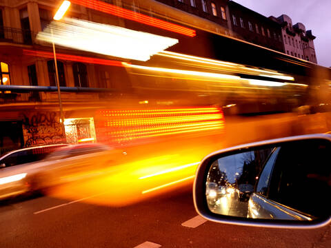 Deutschland, Berlin, Seitenspiegel eines Autos, das in der Abenddämmerung durch die Stadt fährt, lizenzfreies Stockfoto