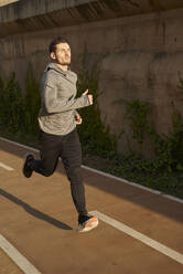 Man running on a road in sunlight - PACF00173