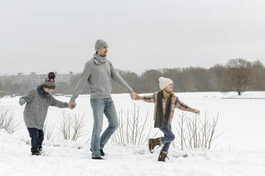 Father and two children walking in winter landscape - EYAF00929