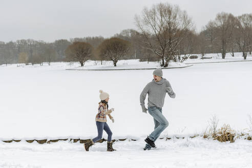 Vater und Tochter laufen in einer Winterlandschaft - EYAF00931