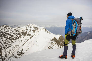 Man standing on the peak of a snowy mountain, Lombardy, Valtellina, Italy - MCVF00219