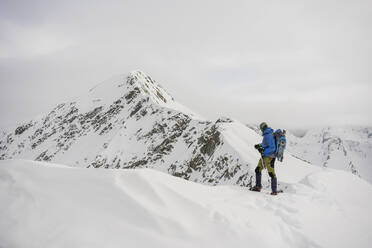 Mann bei einem Ausflug auf dem Kamm eines verschneiten Berges, Lombardei, Valtellina, Italien - MCVF00221
