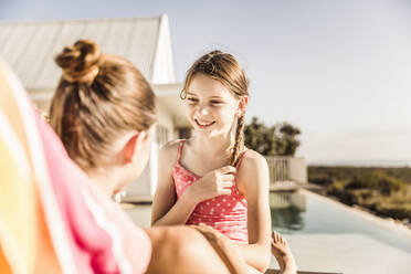 Porträt eines glücklichen Mädchens mit ihrer Mutter am Swimmingpool - SDAHF00126