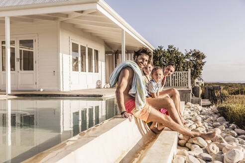 Porträt einer glücklichen Familie am Swimmingpool - SDAHF00129