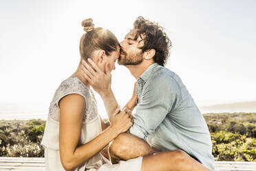 Verliebtes junges Paar auf Terrasse an der Küste im Sommer - SDAHF00136