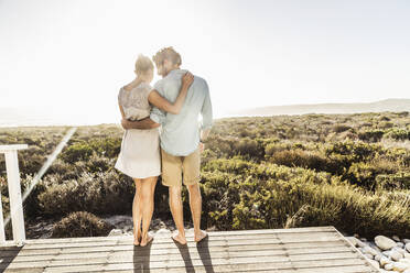 Zärtliches junges Paar, das sich auf einer Terrasse an der Küste im Sommer umarmt - SDAHF00137