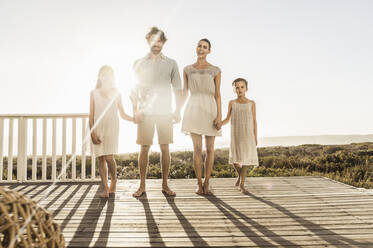 Family standing on terrace at the coast at sunset - SDAHF00142