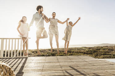 Unbeschwerte Familie auf der Terrasse an der Küste bei Sonnenuntergang - SDAHF00143