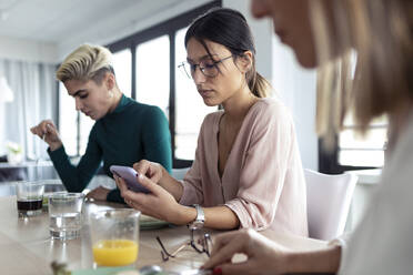 Geschäftsfrau nutzt Smartphone während der Mittagspause im Büro - JSRF00891