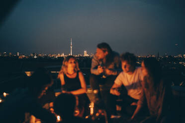 Friends enjoying on terrace against cityscape at dusk - MASF16627