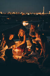 High angle view of friends enjoying rooftop party on illuminated terrace in candlelight - MASF16629