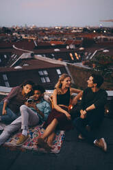 High angle view of friends relaxing together on terrace in city during rooftop party - MASF16643