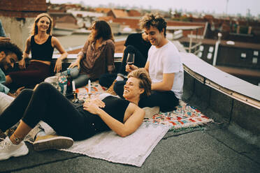 Happy friends relaxing on terrace during rooftop party - MASF16653