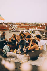 Male and female friends enjoying rooftop party on terrace in city - MASF16657