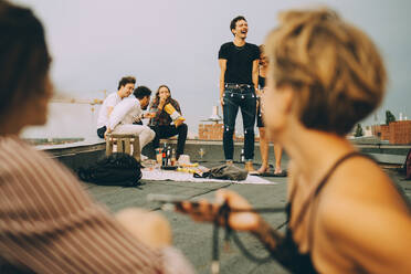 Männliche und weibliche Freunde genießen auf der Terrasse einer Dachterrassenparty - MASF16669