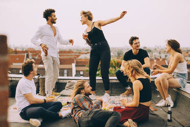 Happy people dancing while enjoying music with friends on terrace at rooftop party - MASF16680