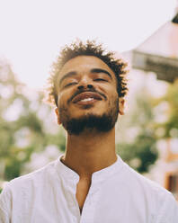 Porträt eines lächelnden jungen Mannes in Freizeitkleidung an einem sonnigen Tag - MASF16696