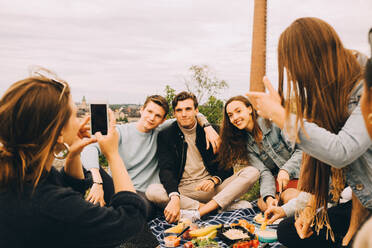 Frau fotografiert Freunde beim gemeinsamen Picknick gegen den Himmel - MASF16715