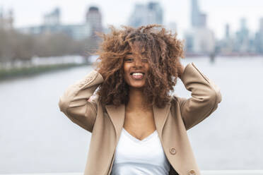 Porträt einer glücklichen jungen Frau mit lockigem Haar, London, UK - WPEF02559