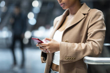 Nahaufnahme einer jungen Frau, die in einer U-Bahn-Station ein Mobiltelefon benutzt - WPEF02564