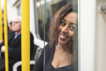 Porträt einer lächelnden jungen Frau in einer U-Bahn - WPEF02567