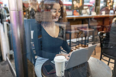 Junge Frau mit Laptop in einem Café - WPEF02571