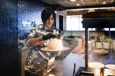 Chef preparing a dish in restaurant kitchen - DGOF00358