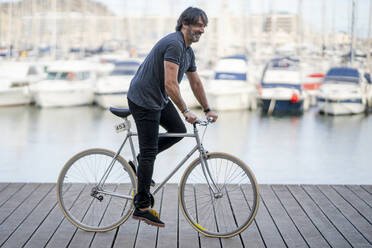 Älterer Mann fährt Fahrrad auf der Strandpromenade, Alicante, Spanien - DLTSF00480