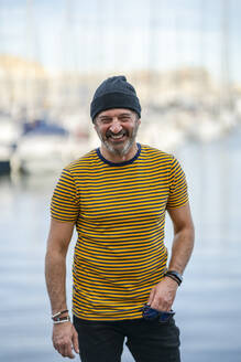 Portrait of laughing mature man wearing cap and striped t-shirt, Alicante, Spain - DLTSF00486