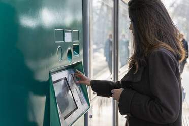 Junge Frau benutzt Fahrkartenautomat an der Straßenbahnhaltestelle - AFVF05295