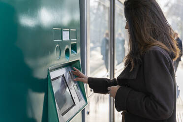 Junge Frau benutzt Fahrkartenautomat an der Straßenbahnhaltestelle - AFVF05296