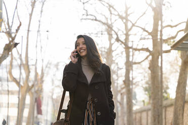 Lächelnde junge Frau beim Telefonieren in der Stadt - AFVF05307