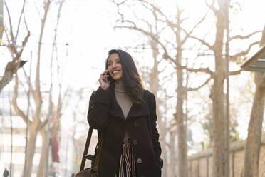 Smiling young woman on the phone in the city - AFVF05307